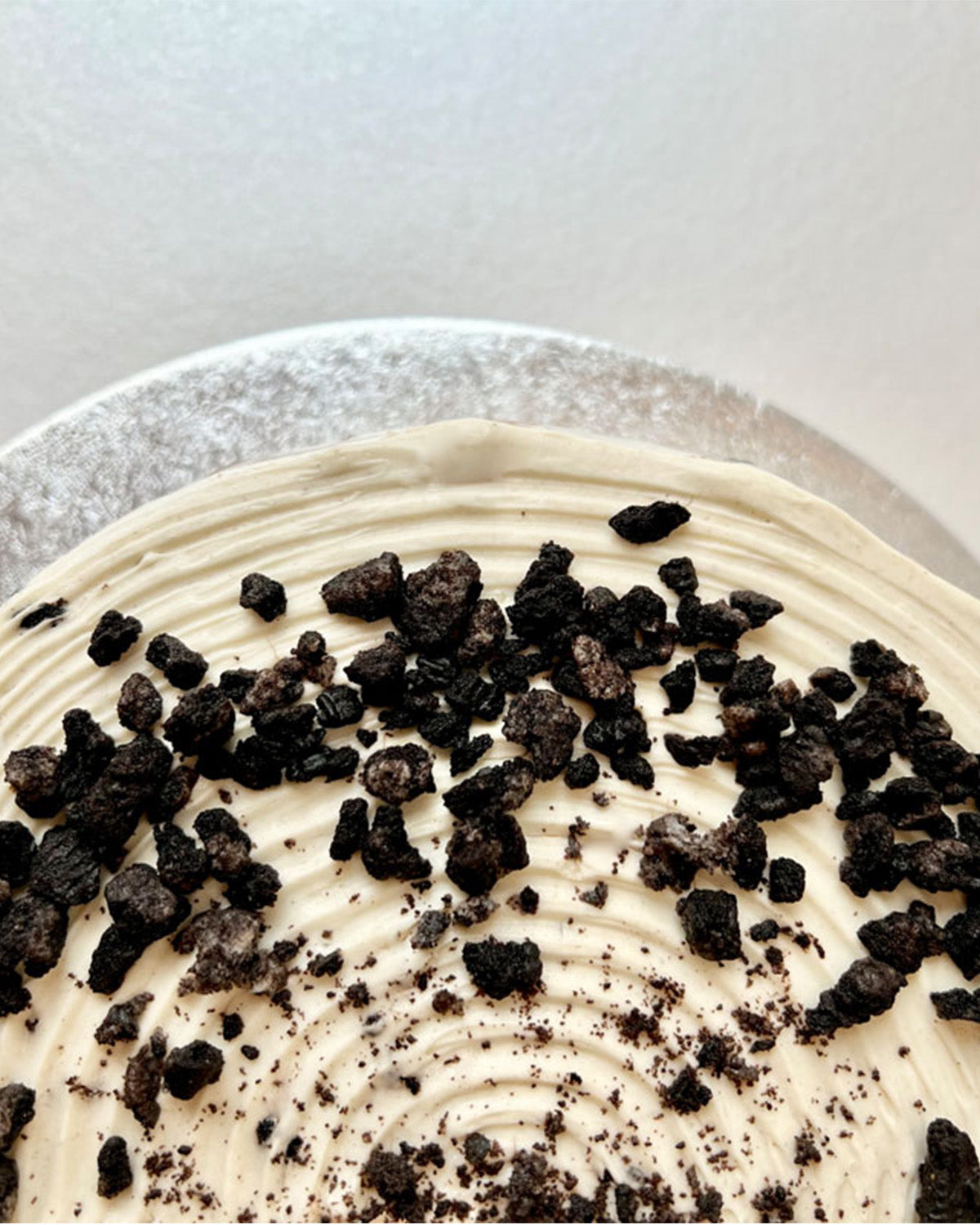 Close-up of a pancake cake with cream and cookie crumb toppings on a white background.