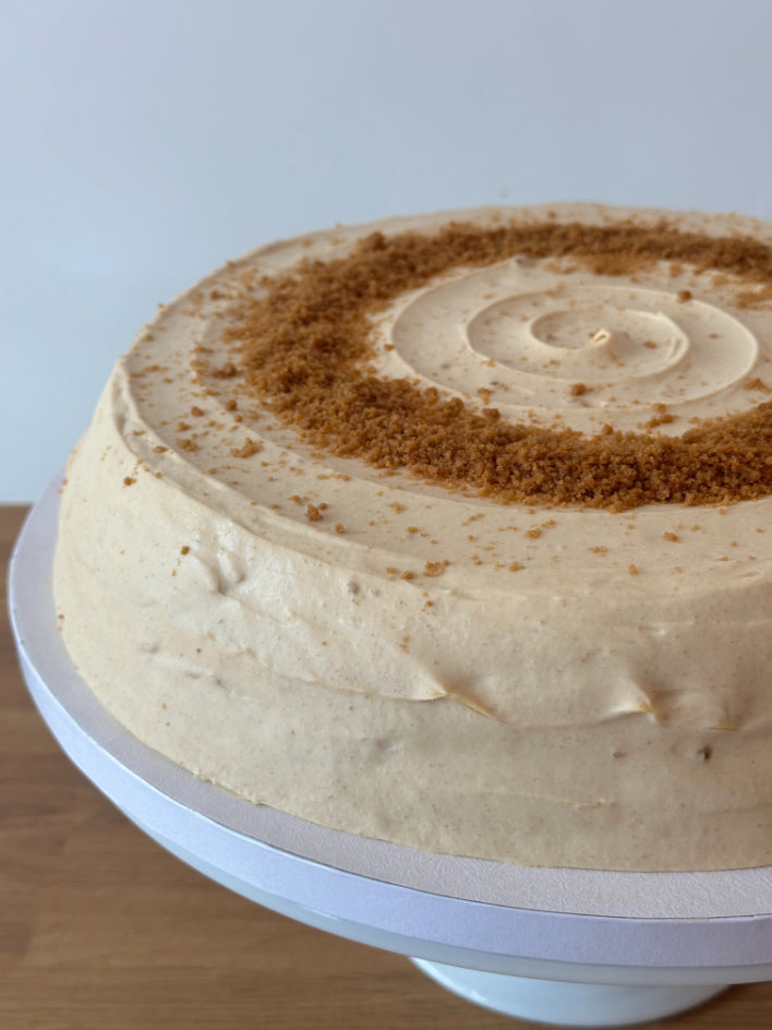Close up of a round biscoff pancake cake on a white cake stand.