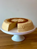 Round biscoff pancake cake with a slice taken out, sat on a white cake stand.