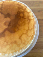 A close-up top-down view of a creme brulee pancake cake, set on a wooden surface.