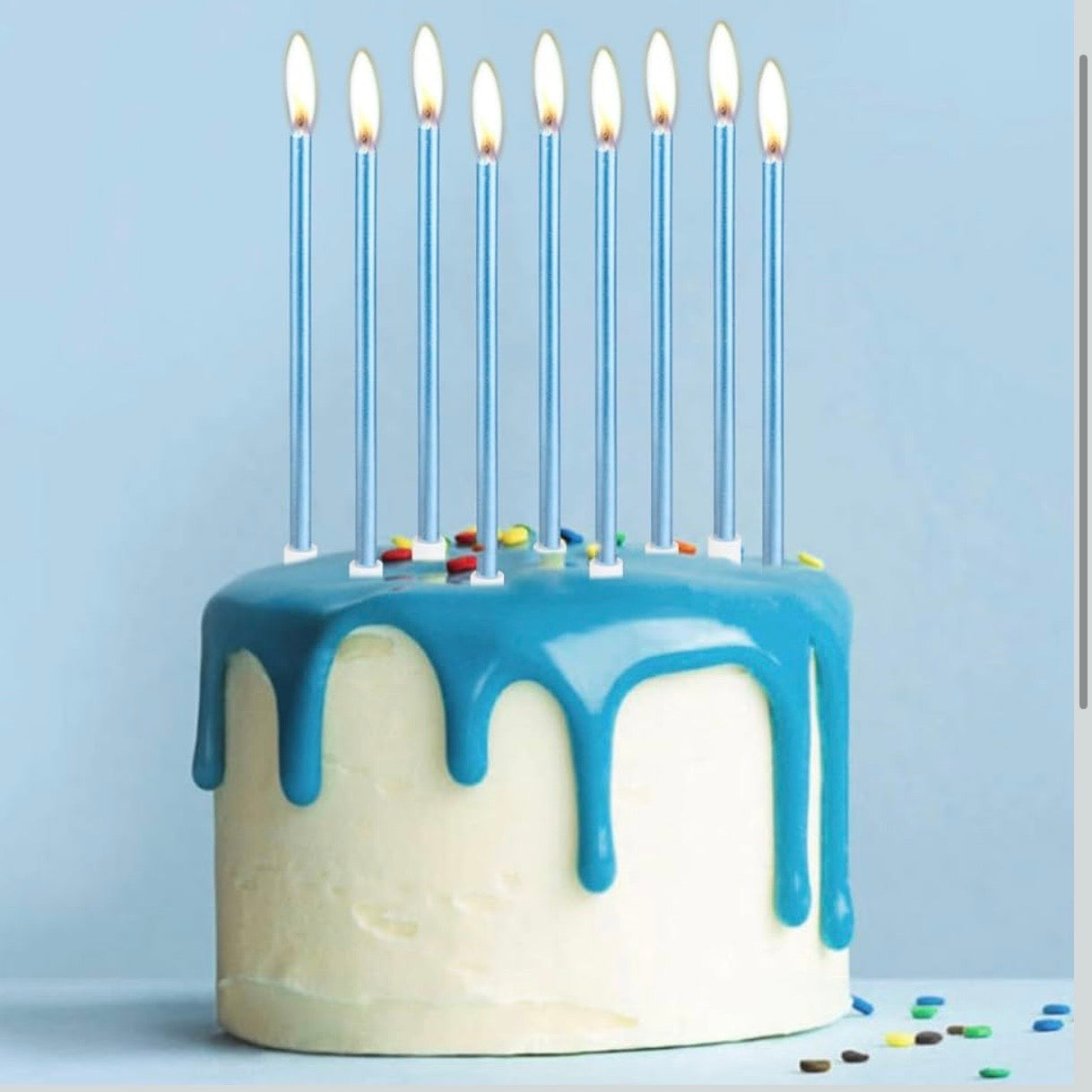 Birthday cake with blue icing and 9 lit blue candles on a light blue background.