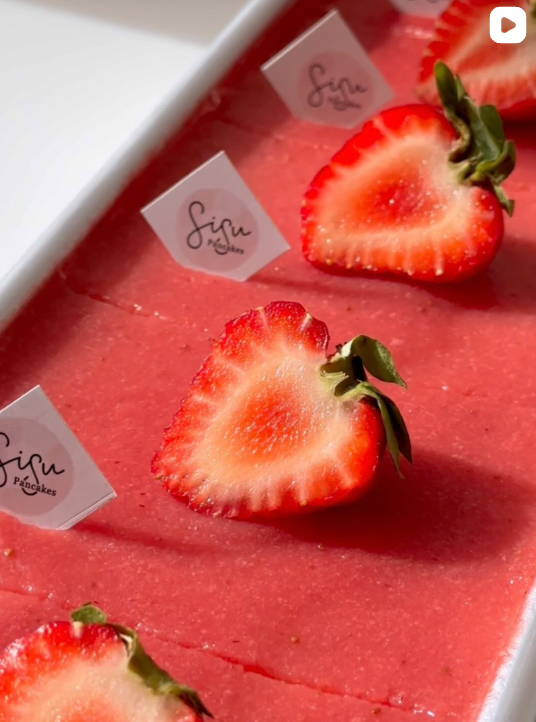 Sliced strawberries on a pink surface with 'Sisu' branding.
