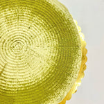 A close-up of a round matcha pancake cake with matcha powder sprinkled on top, sitting on a gold tray.