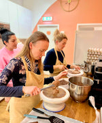 Three women baking in a kitchen.