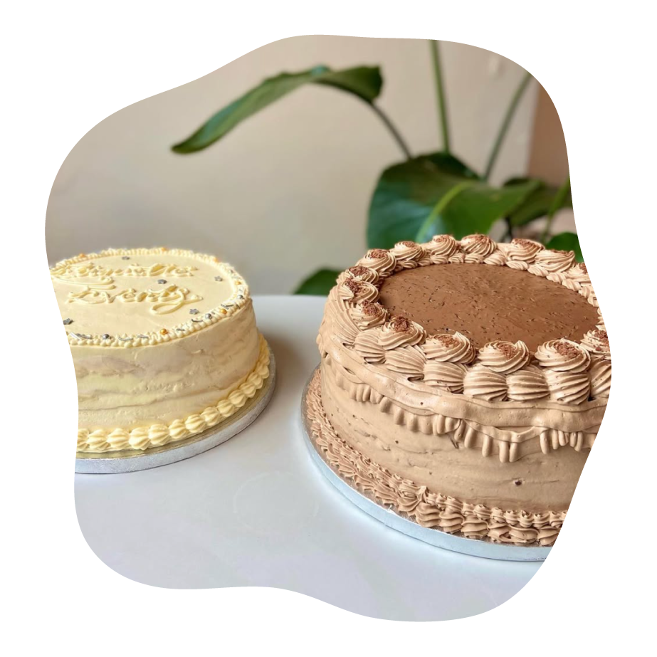 Two pancake cakes on a white surface with a blurred plant in the background
