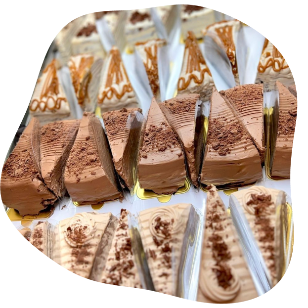 Multiple triangular chocolate pancake cake slices in clear plastic clamshell packaging, arranged on a white surface with some decorated with chocolate drizzle and cocoa powder.