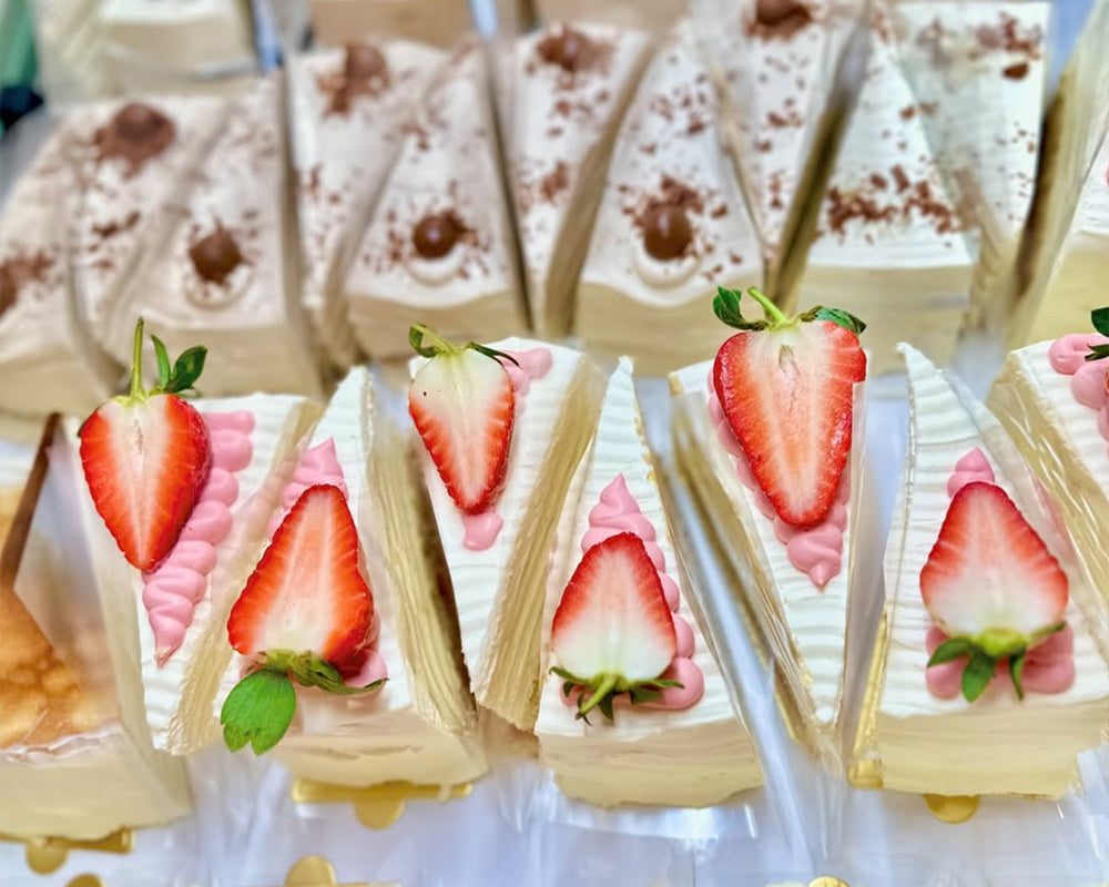 Triangular pancake cake slices with strawberries on a white surface