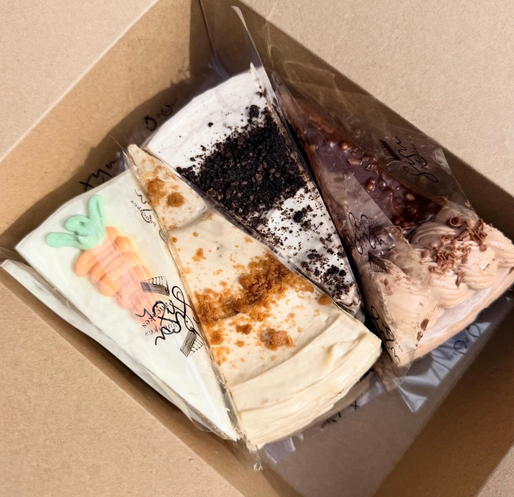 Four slices of different pancake cakes in clear plastic packaging in a cardboard box.